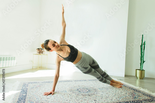 Young attractive smiling woman practicing yoga in a stylish room photo