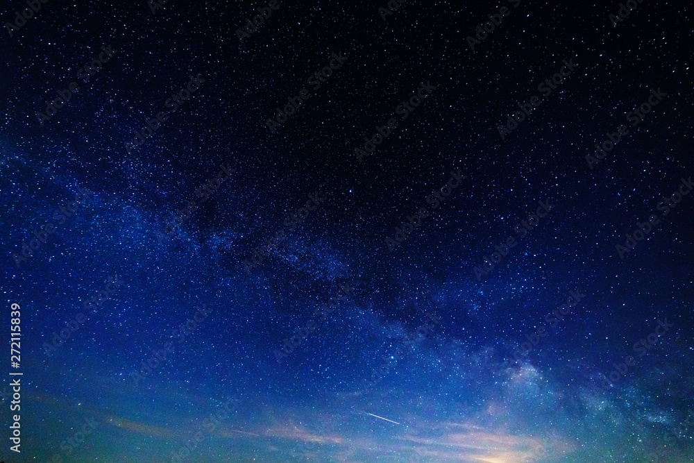 Fototapeta premium Starry sky and the milky way over the meadow and forest.