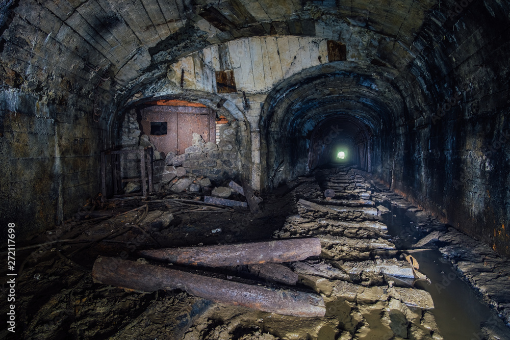 Dark abandoned coal mine with rusty remnants of equipment