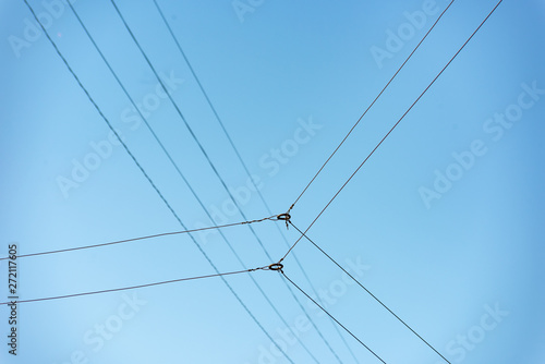 Intersecting wires with metal ring against a blue sky