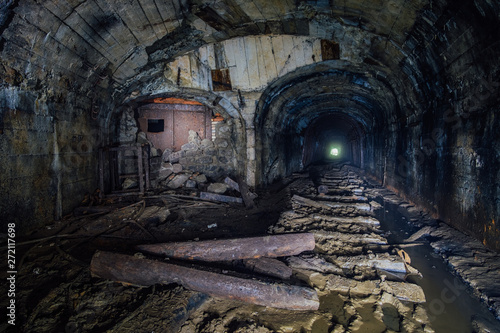Dark abandoned coal mine with rusty remnants of equipment