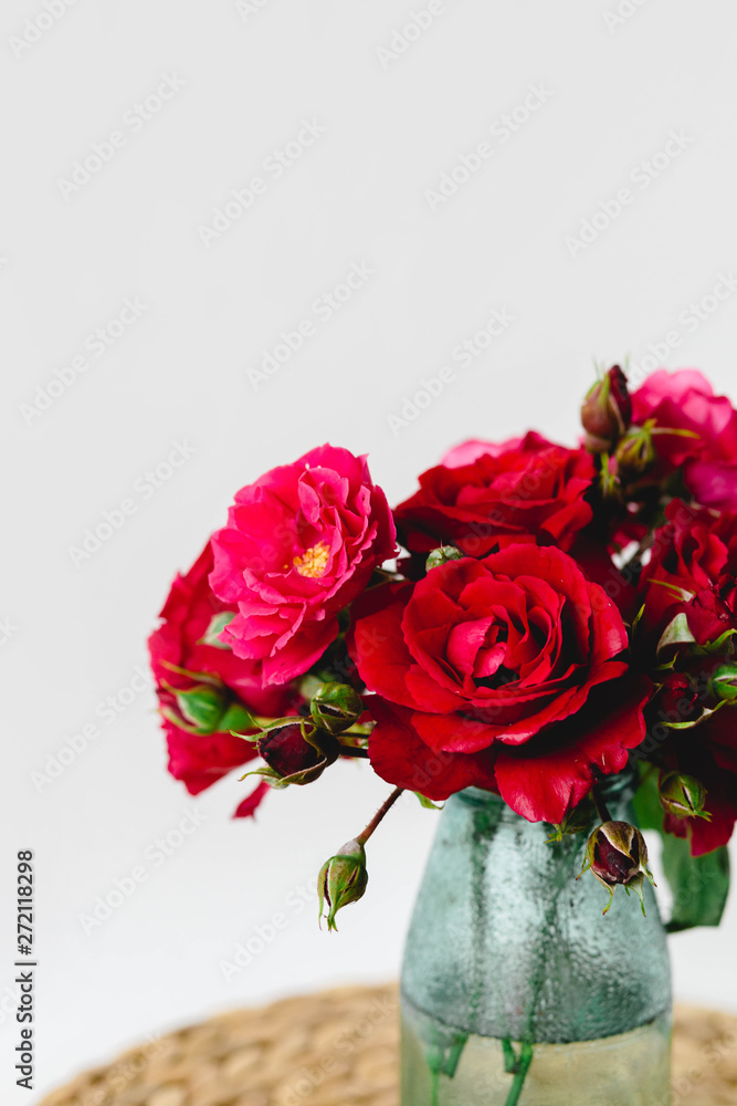 Coloful roses in vase on a wicker napkin on white background Coloful roses in vase on a wicker napkin on white background