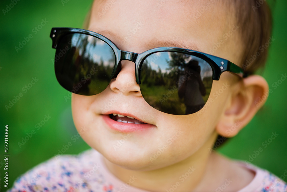 Baby with sunglasses on the green grass background on a sunny day, lifestyle Baby with sunglasses on the green grass background on a sunny day, lifestyle