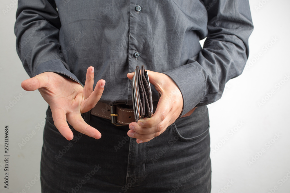 Upset young man in shirt holding empty wallet over white background