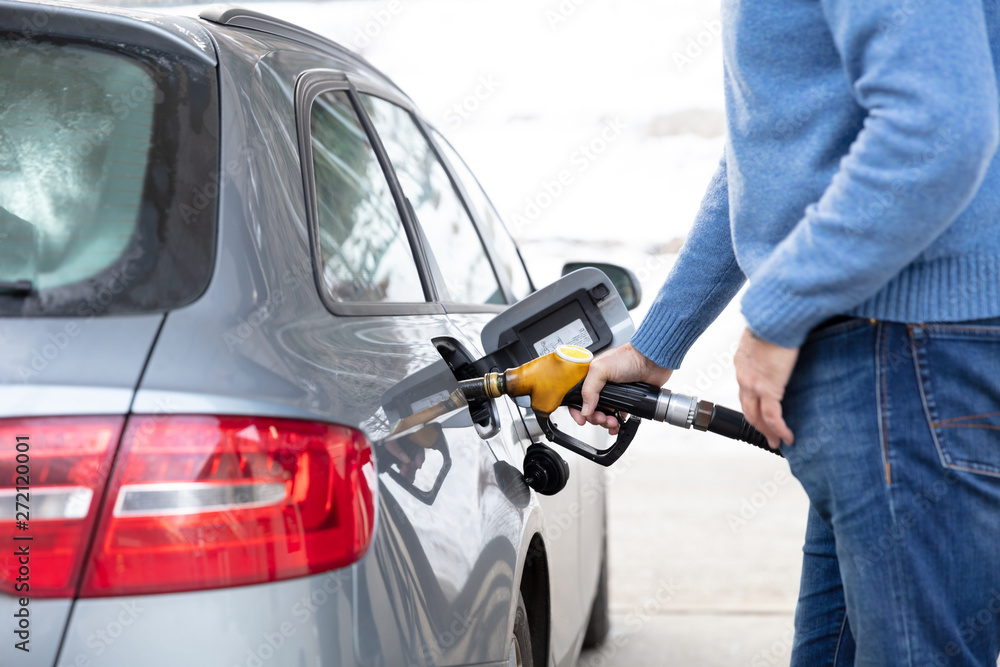 Man pumping gas into his vehicle Man pumping gas into his vehicle