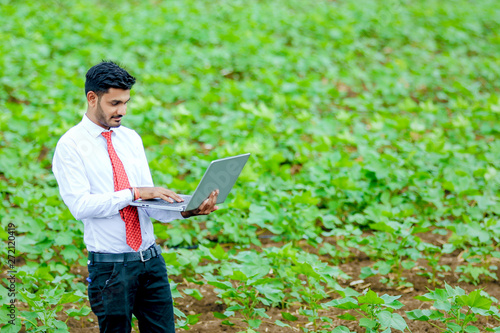 agronomist with laptop at cotton field