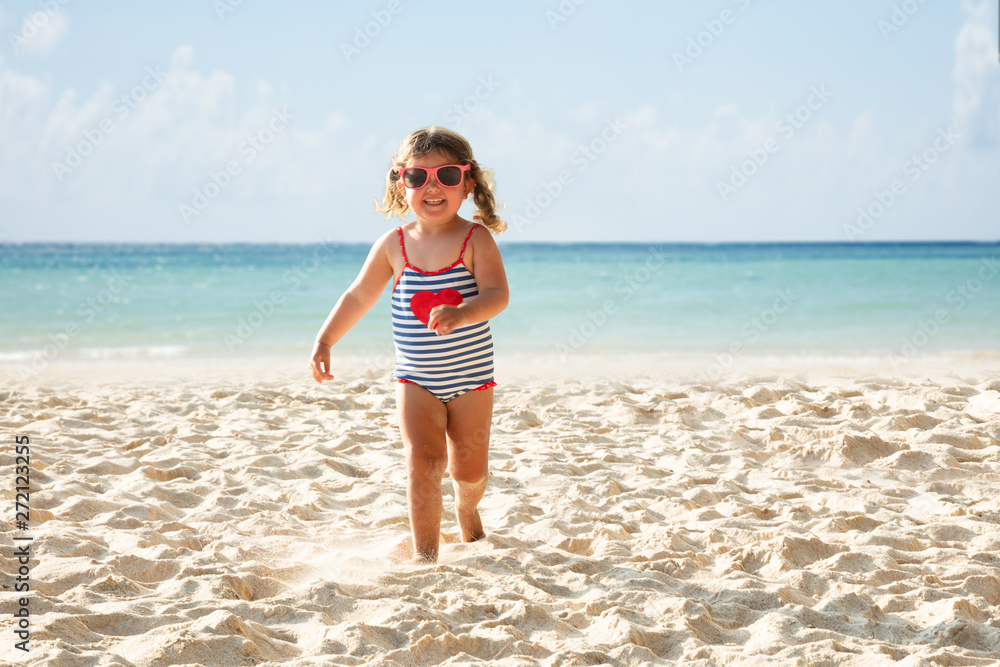 Portrait Of A Smiling Toddler Girl Running On Beach
