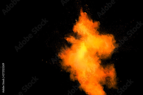 Orange color powder splatter on black background. Color particles splash.