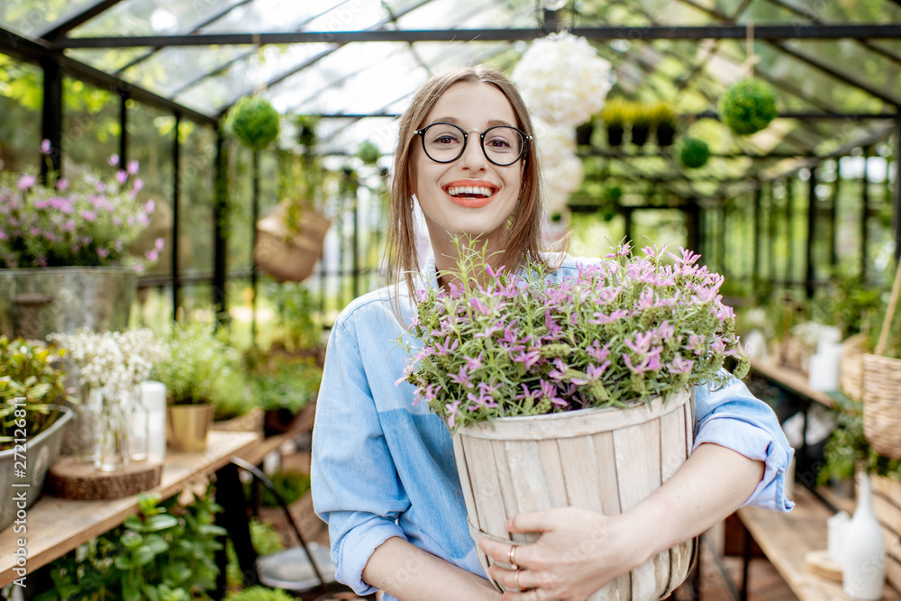 Portrait of a young woman standing with lavender at the entrance of the beautiful greenhouse or flower shop