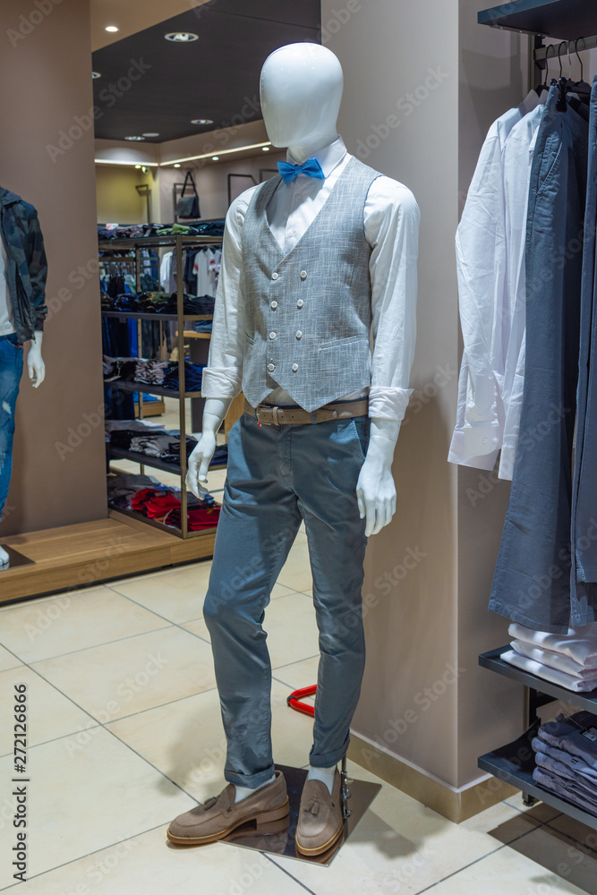 White mannequin in a fashion store with grey vest and blue bow tie.