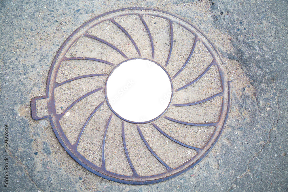 Manhole cast iron heavy lilac with a pattern of divergent rays on the background of gray asphalt. In the center of the round white background for photo inscription