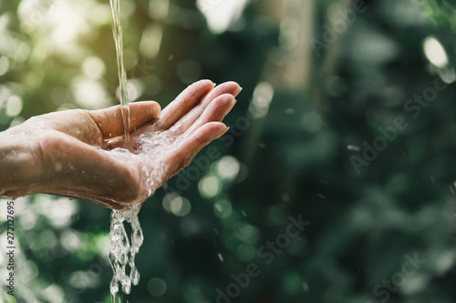closeup water flow to hand of women for nature concept on the garden background.