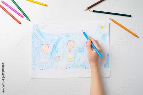 Child draws a pencil drawing of the house and his family. New home.