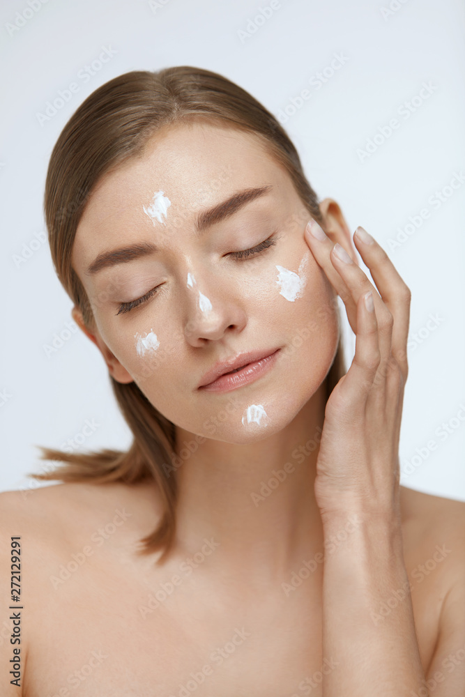 Skin care. Woman applying facial cream on beauty face closeup Skin care. Woman applying facial cream on beauty face closeup