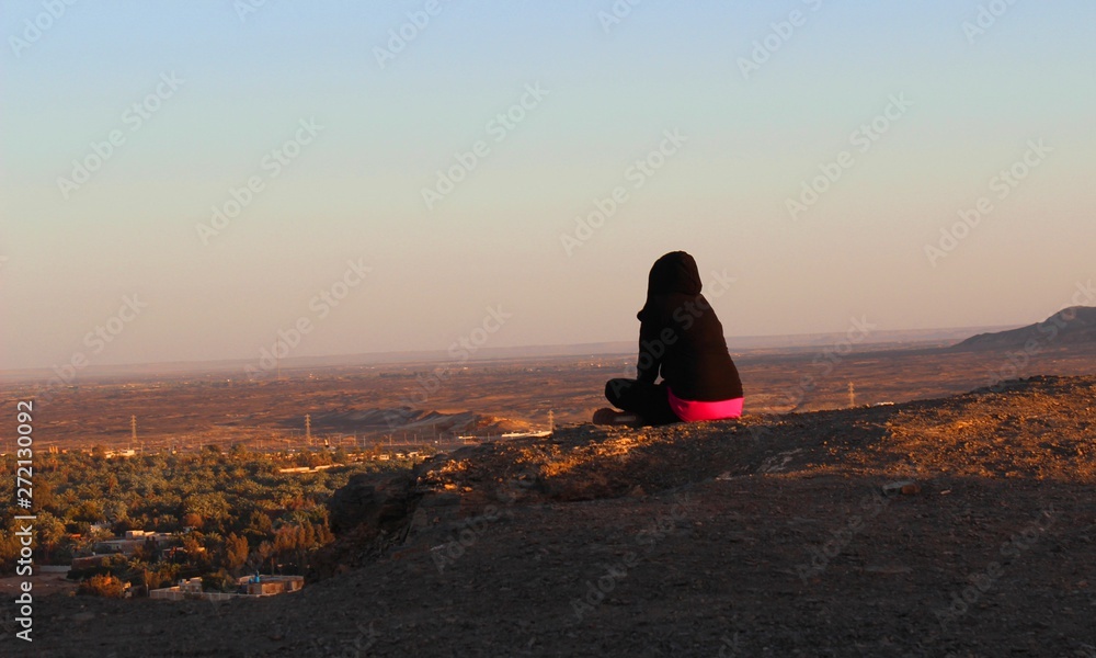 Girl watching sunset in the evening from the top of the mountain in Baharia oasis