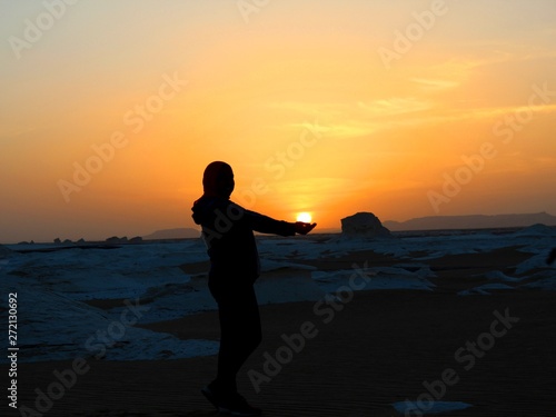 Girl holding the sun in her hand in the sunset in the desert