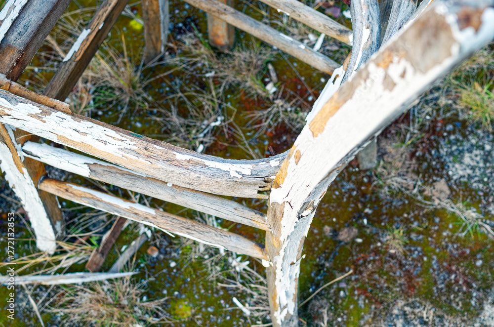 Broken chair in a garden that has rotted and the paint goes off