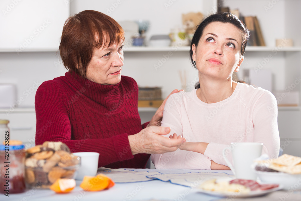 Portrait of sad mature woman talking with daughter