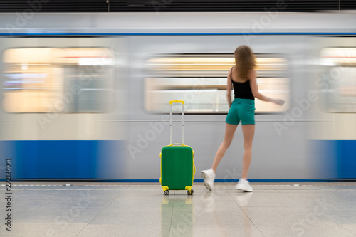green bright road suitcase. A young beautiful girl walks around him and an action takes place. Blurred motion, very impressive. Lots of copy space © Денис Бухлаев