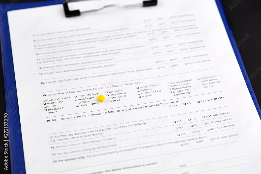 Small round yellow pill on medical questionnaire form Small round yellow pill on medical questionnaire form
