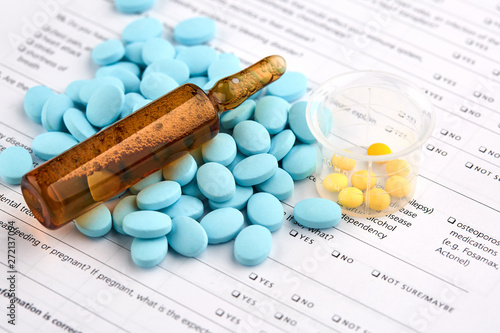 Brown ampoule and colorful pills on medical questionnaire form