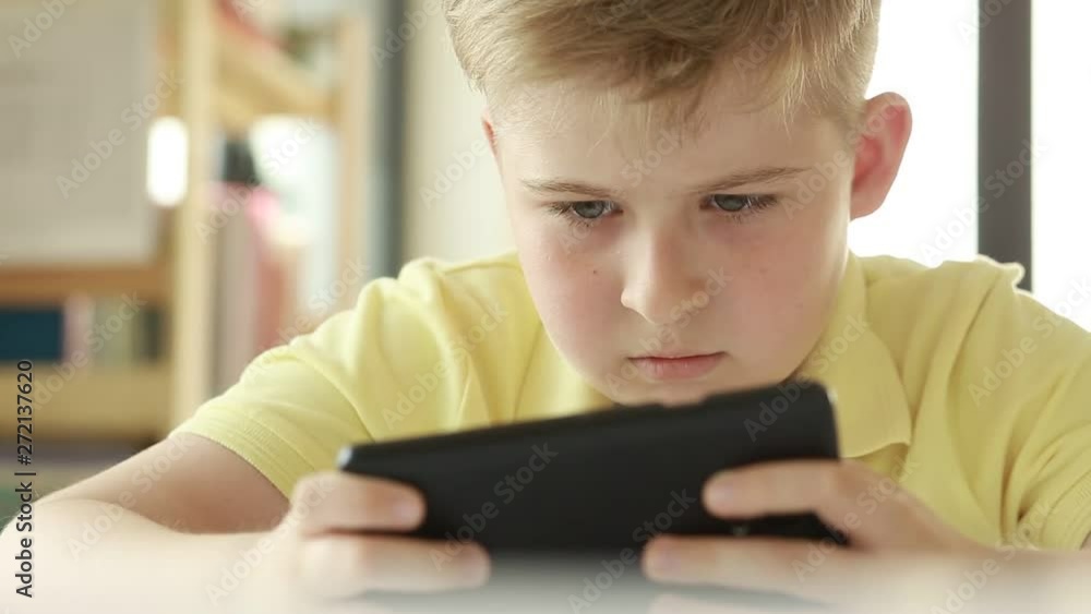 Child looking at a smart phone. Boy use a mobile phone. Internet gaming disorder. Child looking at a smart phone. Boy use a mobile phone. Internet gaming disorder.