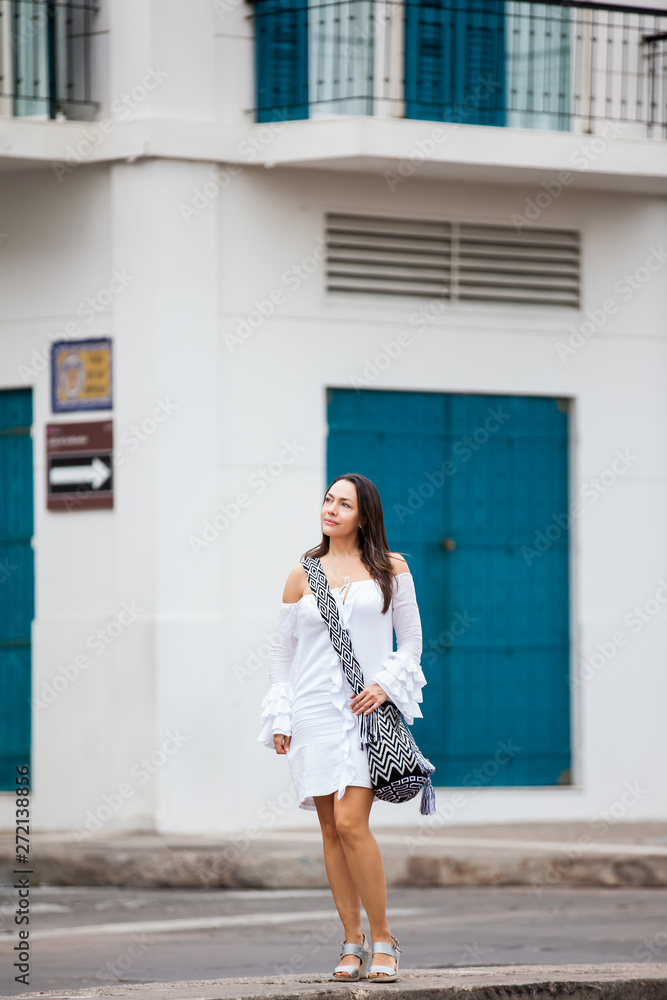 Beautiful woman on white dress walking alone at the streets of the colonial walled city of Cartagena de Indias Beautiful woman on white dress walking alone at the streets of the colonial walled city of Cartagena de Indias