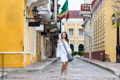 Beautiful woman on white dress walking alone at the streets of the colonial walled city of Cartagena de Indias © anamejia18