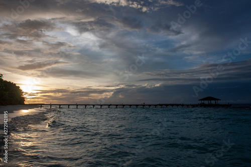 Silhouette of the long pier, bridge, on the background of a sunset on Maldives Islands. Night landscape. 