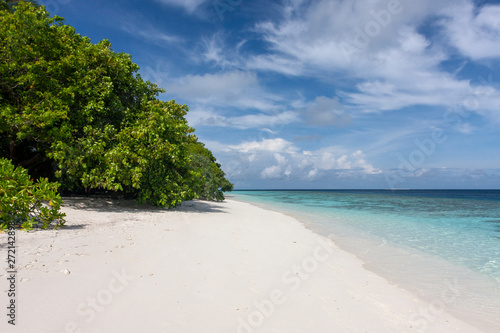 Fototapeta Naklejka Na Ścianę i Meble -   Idyllic tropical scene with beautiful green palm trees leaning over white sand beach, Maldives. Beautiful Maldives Beach with lush green palm tress and clear blue waters.