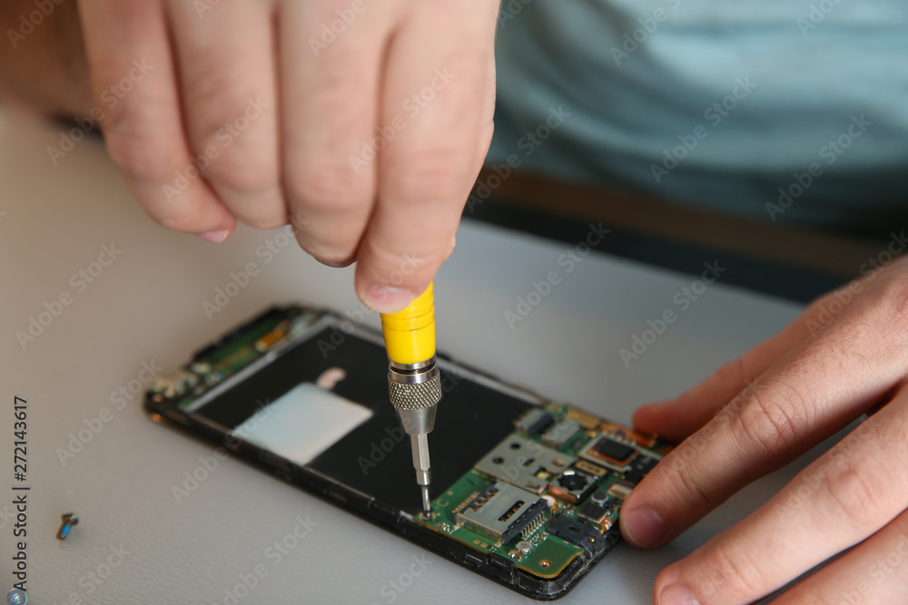Technician repairing mobile phone at table, closeup Technician repairing mobile phone at table, closeup