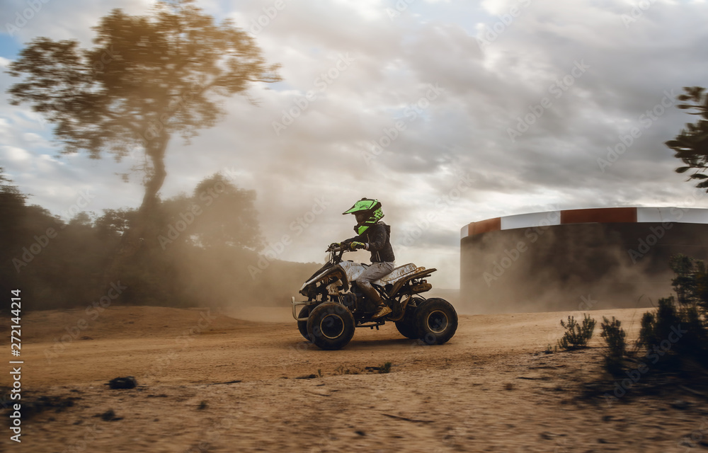 A child rides a quad bike through the mud. ATV rider rides on the dirt A child rides a quad bike through the mud. ATV rider rides on the dirt