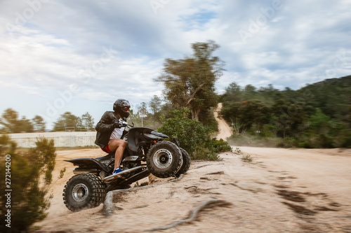 The quad racer is jumping on the dusty road. Quad bike off-road. Quad bike in action.
