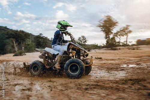 A child rides a quad bike through the mud. ATV rider rides on the dirt
