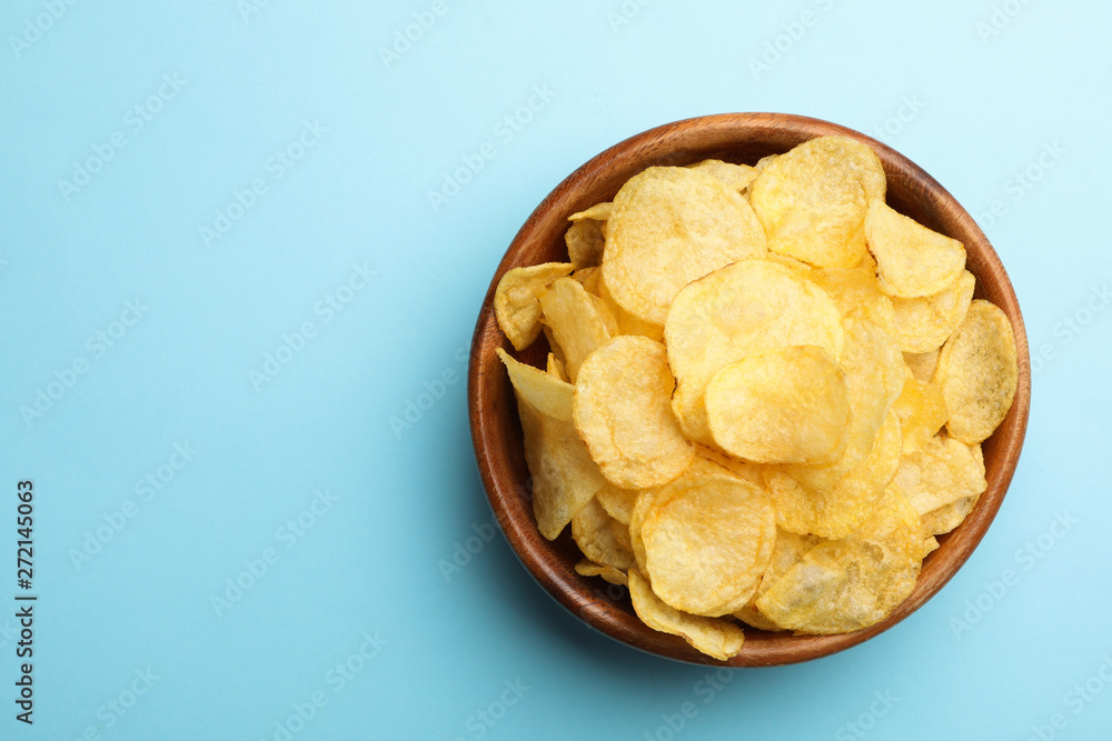Delicious crispy potato chips in bowl on color background, top view with space for text Delicious crispy potato chips in bowl on color background, top view with space for text
