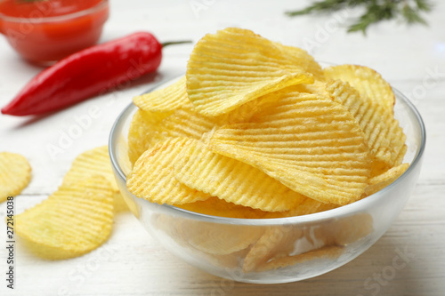 Delicious crispy potato chips in bowl on table, closeup