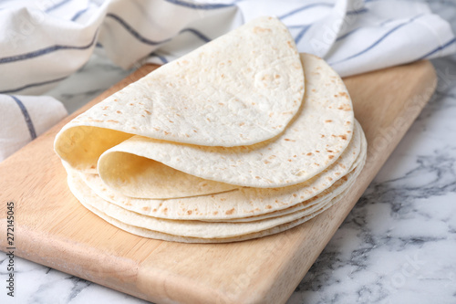 Wooden board with corn tortillas on marble table. Unleavened bread