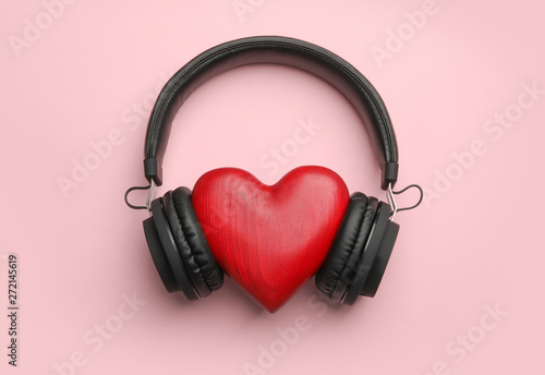 Decorative heart and modern headphones on color background, flat lay