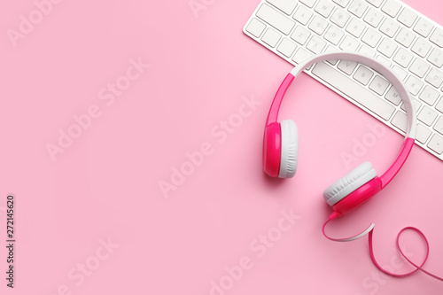 Modern headphones and keyboard on color background, flat lay. Space for text