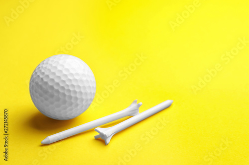 Golf ball and tees on color background, space for text. Sport equipment
