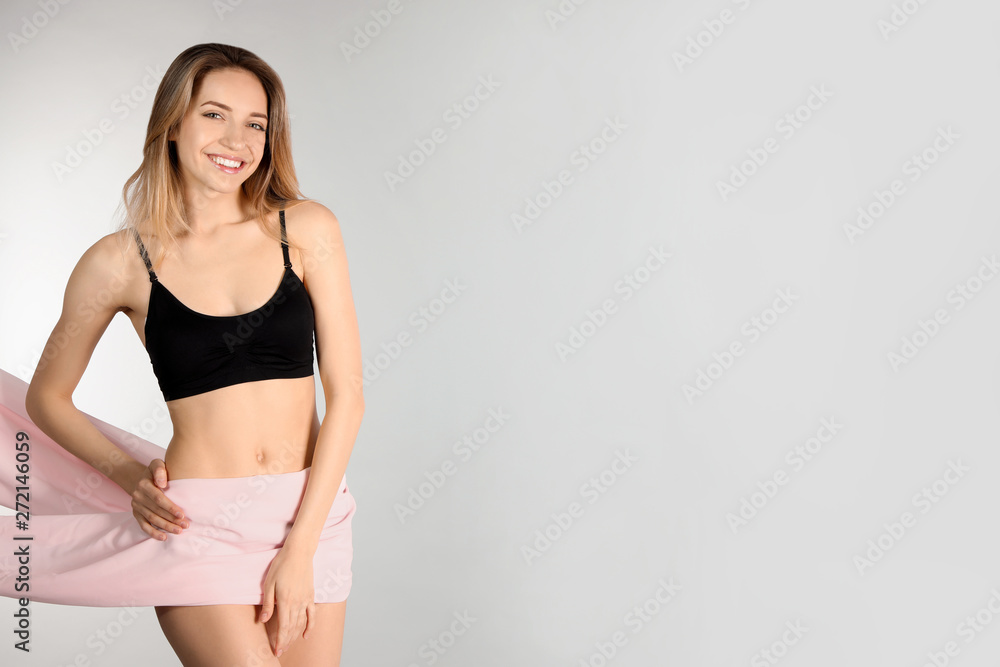 Young slim woman covering her body with fabric on light background. Space for text Young slim woman covering her body with fabric on light background. Space for text