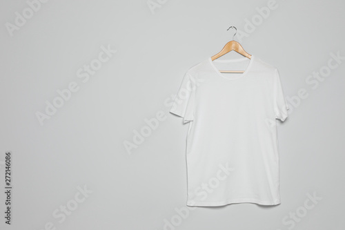Hanger with blank t-shirt on gray background. Mock up for design