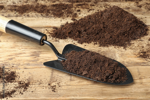 Metal gardening trowel with soil on wooden table