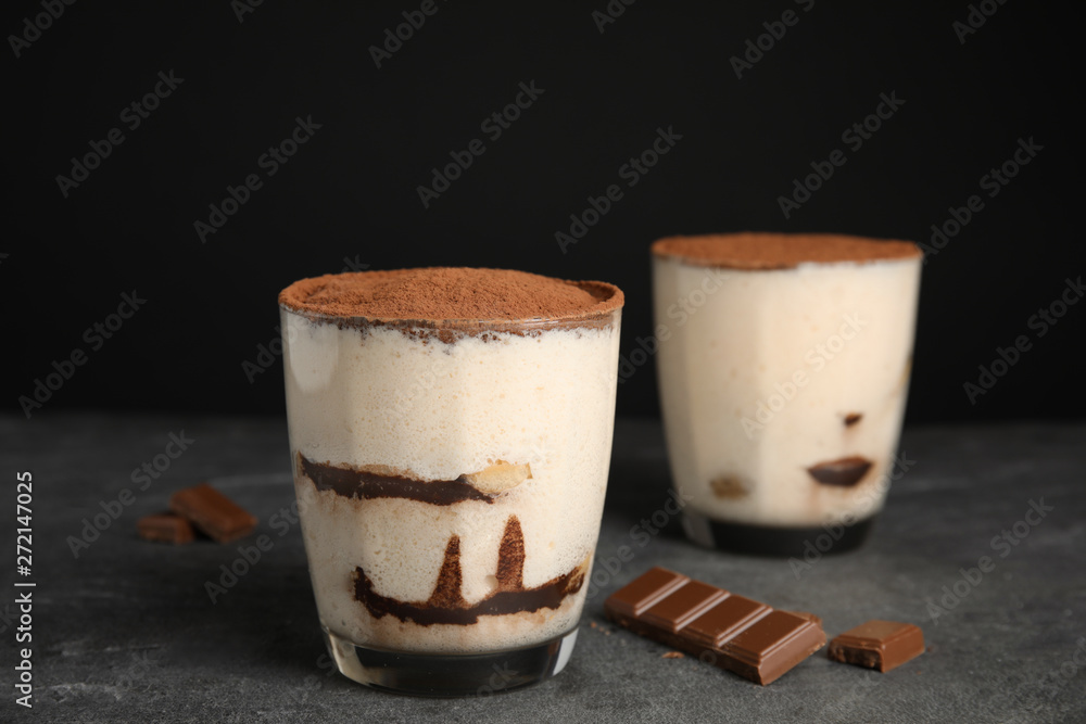 Two glasses of tiramisu cake on table against dark background Two glasses of tiramisu cake on table against dark background
