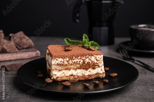 Composition with tiramisu cake on table against dark background photo