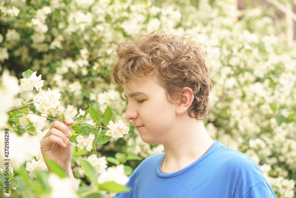 young man stands among the flowers and enjoys summer and flowering young man stands among the flowers and enjoys summer and flowering