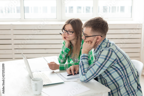 Dissatisfied young husband and wife recount utility bills for payment of an apartment and write the results in a notebook and laptop in their home accounting.