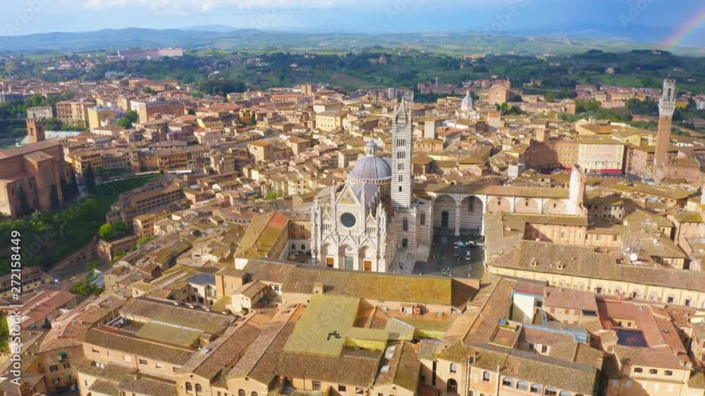 Tuscany, Italy. Aerial circling view of Siena with Duomo of Siena after the rain with a rainbow on the sky at sunset Tuscany, Italy. Aerial circling view of Siena with Duomo of Siena after the rain with a rainbow on the sky at sunset