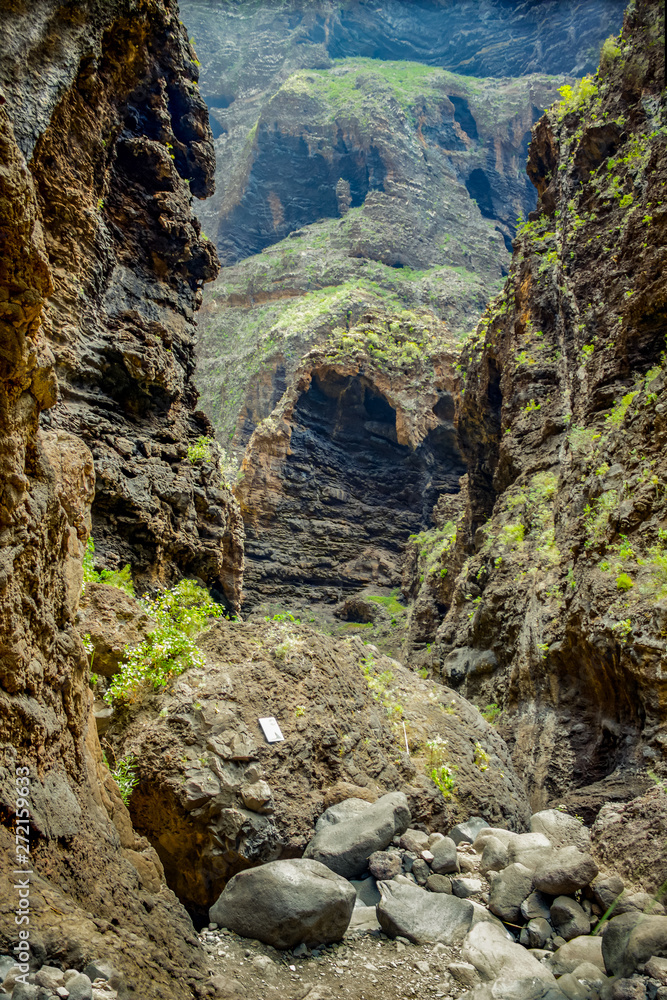 Rocks in the Masca gorge, Tenerife, showing solidified volcanic lava flow layers and arch formation. The ravine or barranco leads down to the ocean from a 900m altitude. Rocks in the Masca gorge, Tenerife, showing solidified volcanic lava flow layers and arch formation. The ravine or barranco leads down to the ocean from a 900m altitude.