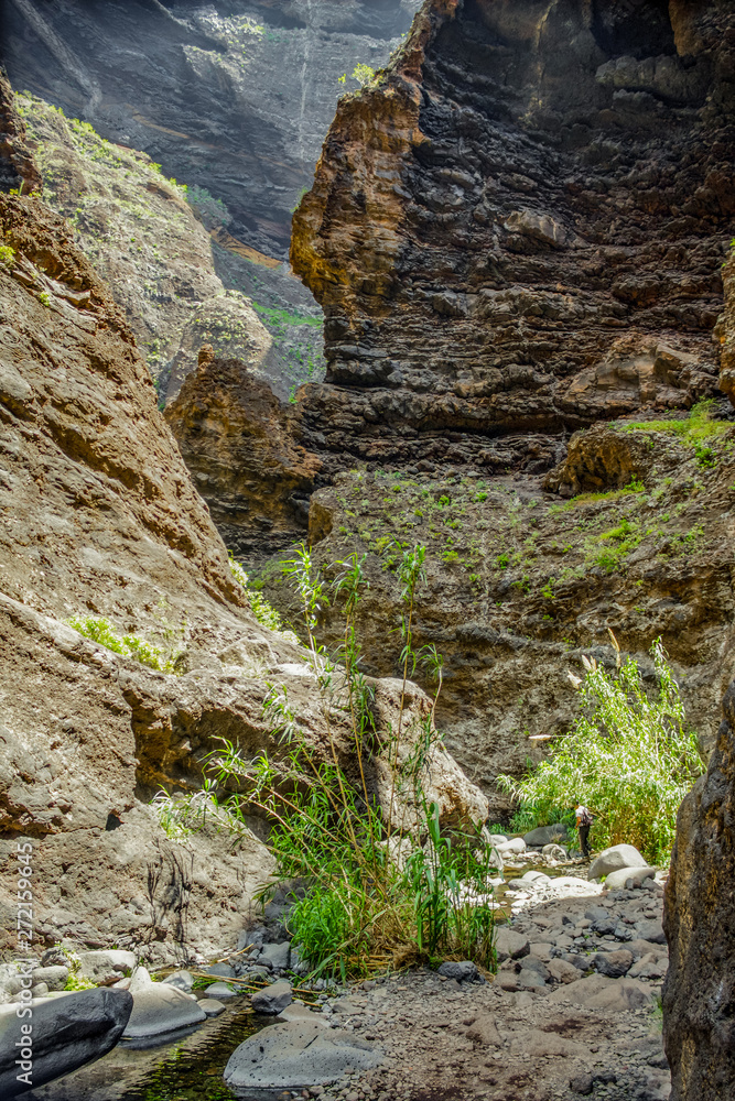 Rocks in the Masca gorge, Tenerife, showing solidified volcanic lava flow layers and arch formation. The ravine or barranco leads down to the ocean from a 900m altitude. Rocks in the Masca gorge, Tenerife, showing solidified volcanic lava flow layers and arch formation. The ravine or barranco leads down to the ocean from a 900m altitude.